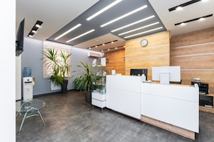 Zona de recepción con un mostrador de madera, un reloj y un dispensador de agua.