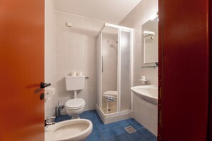 Ein Badezimmer mit Toilette, Bidet, Dusche und Waschbecken.