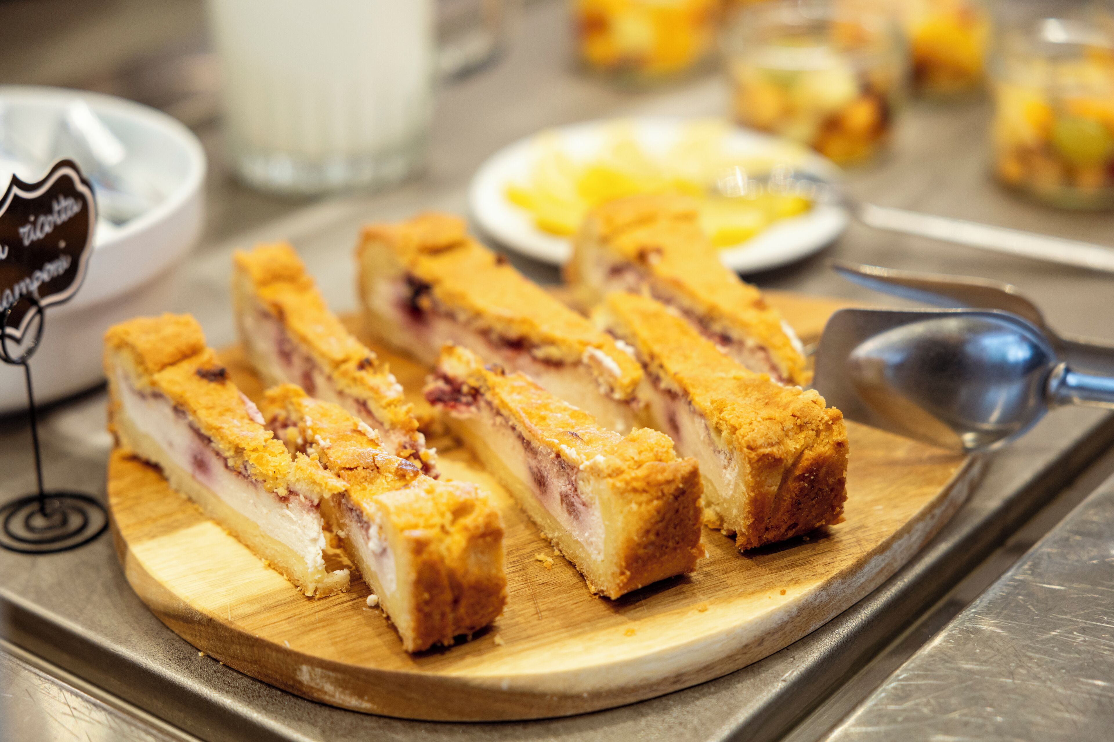Une planche à découper en bois sur laquelle sont disposées des pâtisseries tranchées, le tout présenté sur un plateau en métal.