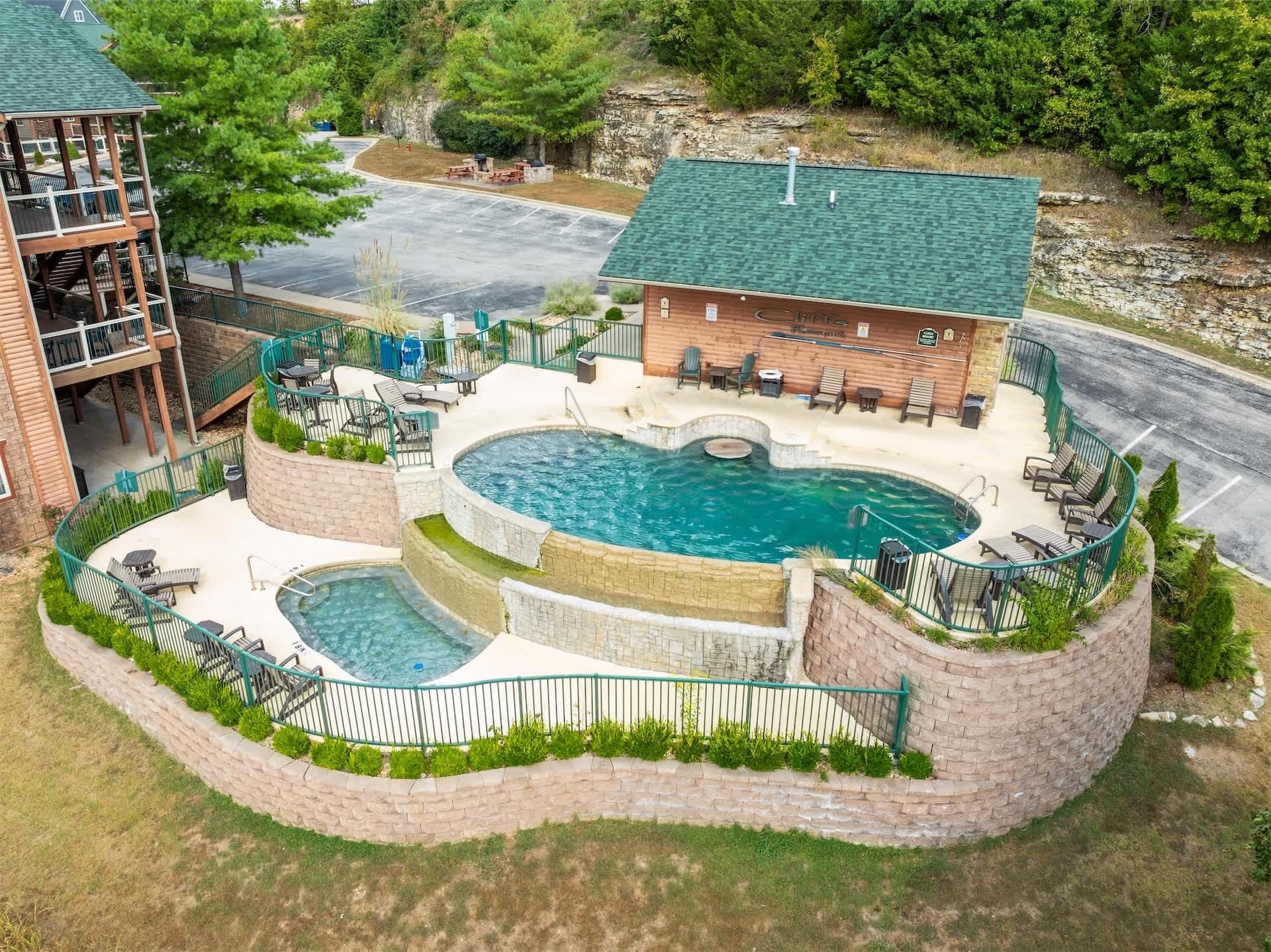 A pool area with a hot tub, lounge chairs, and a building with a green roof.