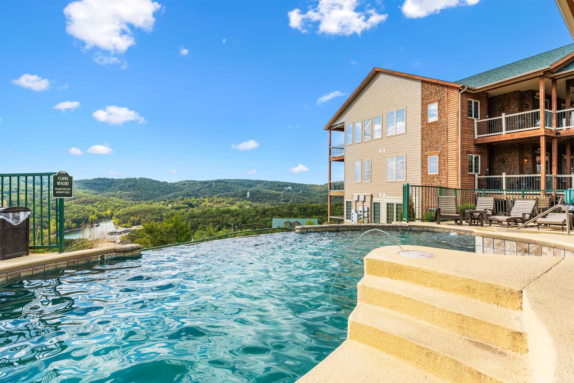 A hotel with a pool, outdoor seating, and a view of the mountains.