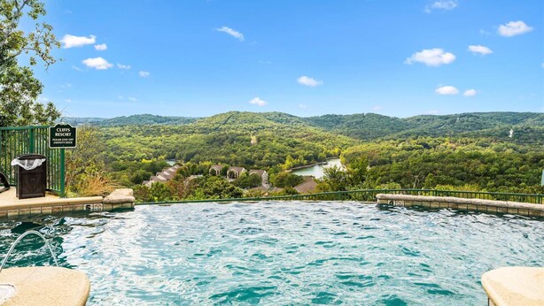 Una piscina con vista su un paesaggio boschivo e un cartello che indica la località come 'Cliffs Resort'.