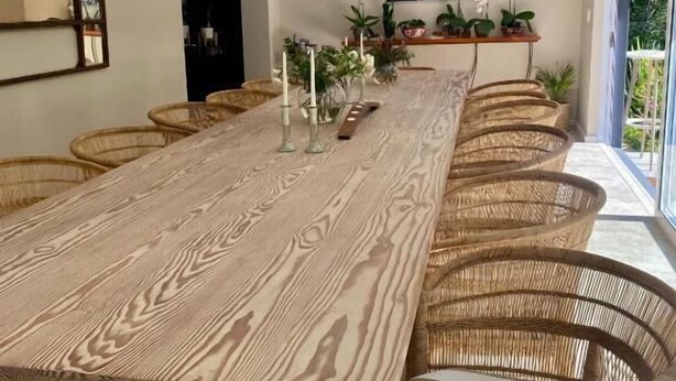Zona pranzo con un lungo tavolo di legno, sedie in vimini e lampade a sospensione in vimini.
