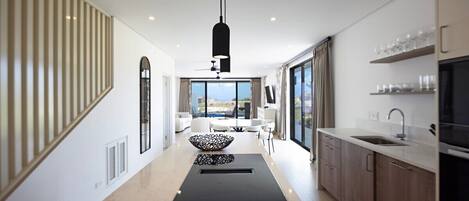 A modern kitchen with a central island, a dining area with a view, and a large window.