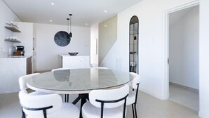 A modern kitchen with white cabinets, a round glass table, and white chairs. - Lancaster Mews 1 (Westmoreland)
