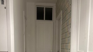 A hallway with a carpeted floor, a white door at the end, and a patterned wall to the right. - House - Central Stamford - Sleeps 4 - Parking (Stamford)