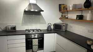 A kitchen with white cabinets, a gas stove, a kettle, a toaster, and a microwave. - House - Central Stamford - Sleeps 4 - Parking (Stamford)