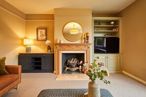 A living room with a fireplace, a sofa, a coffee table, a lamp, and a bookshelf. - Host Stay Tree Tops (Darlington)