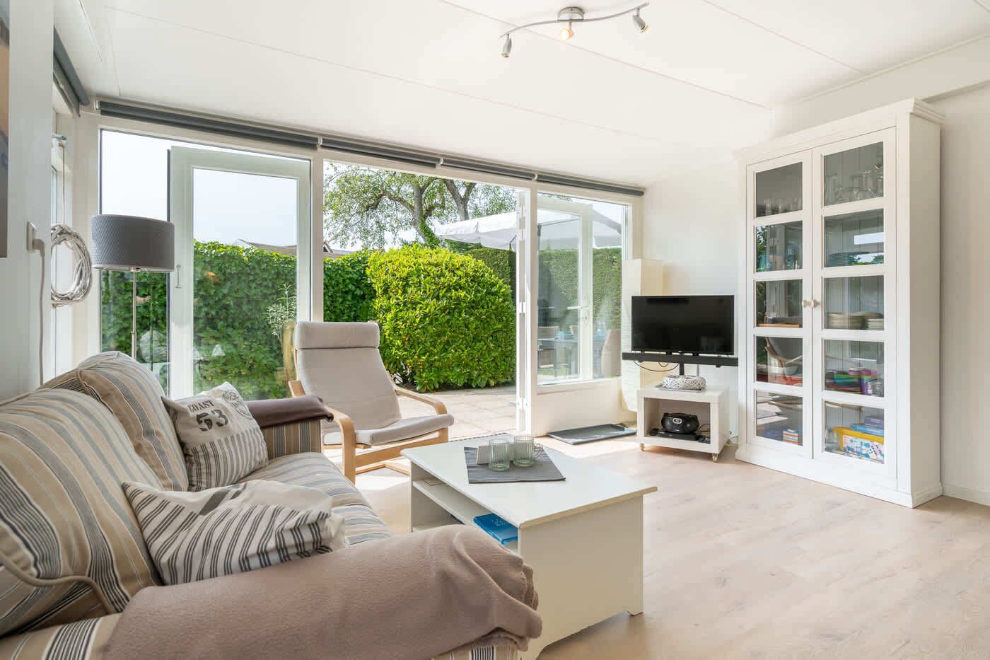 Ein modernes Wohnzimmer mit einer Couch, einem Sessel, einem Couchtisch, einem Fernseher und Glastrennwänden.