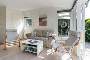 Ein modernes Wohnzimmer mit einer Couch, zwei Sesseln, einem Couchtisch und einem Bücherregal.