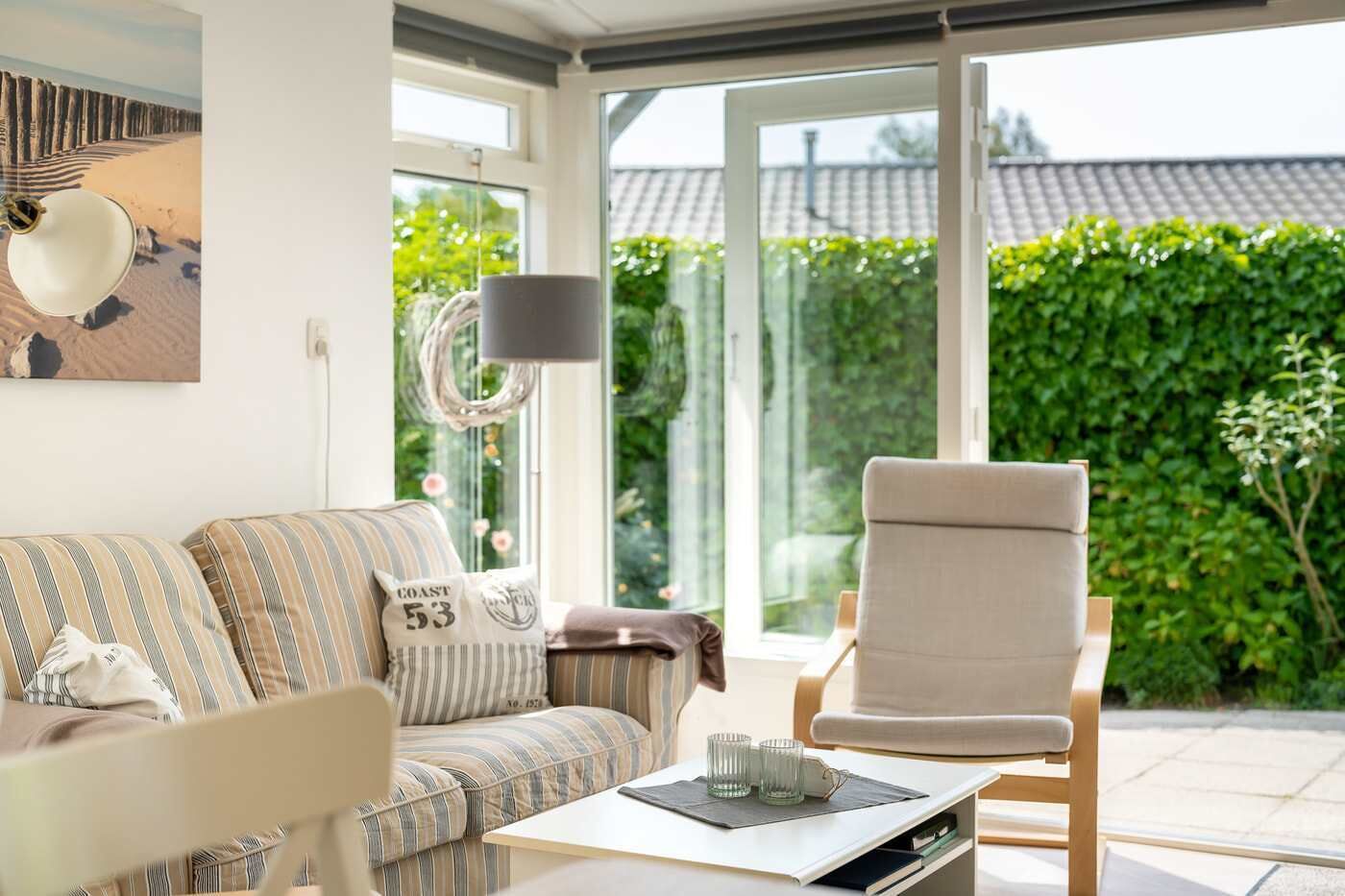 A living room with a sofa, armchair, and a table with glasses.