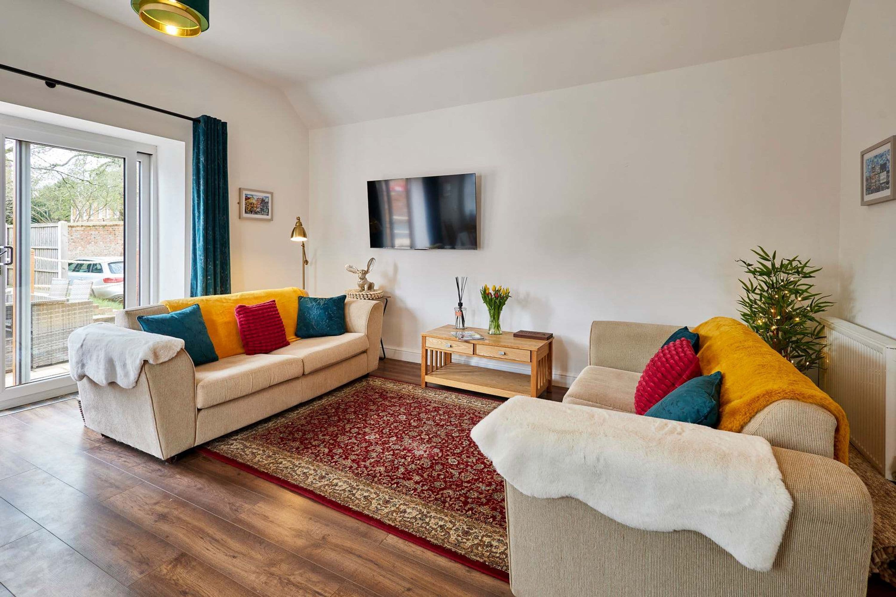 Una sala de estar con un sofá, una mesa de centro, un televisor y una ventana con cortinas.
