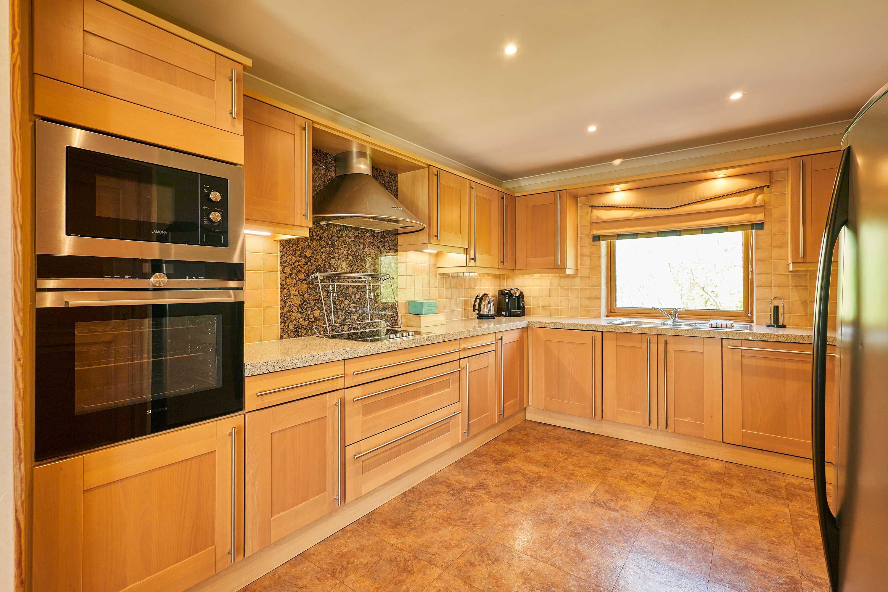 A modern kitchen with wooden cabinets, stainless steel appliances, a granite countertop, and a window providing natural light.