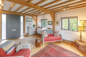 Una habitación acogedora con techo de madera, un sofá rojo, una mesa blanca y una ventana con vistas a árboles.