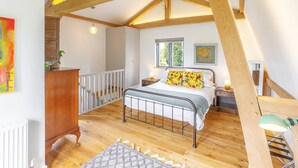A bedroom with a wooden ceiling, a bed, a nightstand, a dresser, and a window. - Host Stay Tree House (Lewes)
