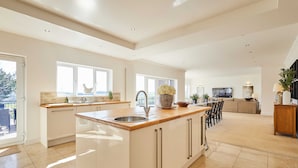 A spacious kitchen with a central island, large windows, and a view of the outdoors. - Host Stay Forest View Lodge (Durham)