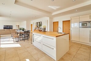 Una cocina moderna con armarios blancos, encimera de madera y horno empotrado.