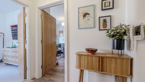 A hallway with wooden doors, a console table with a bowl, and framed artwork on the wall. - Host Stay Austin House (Norwich)