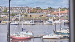 A marina with multiple boats docked, a building in the background, and a clear sky. - Host Stay Paylors View Cottage (Whitby)