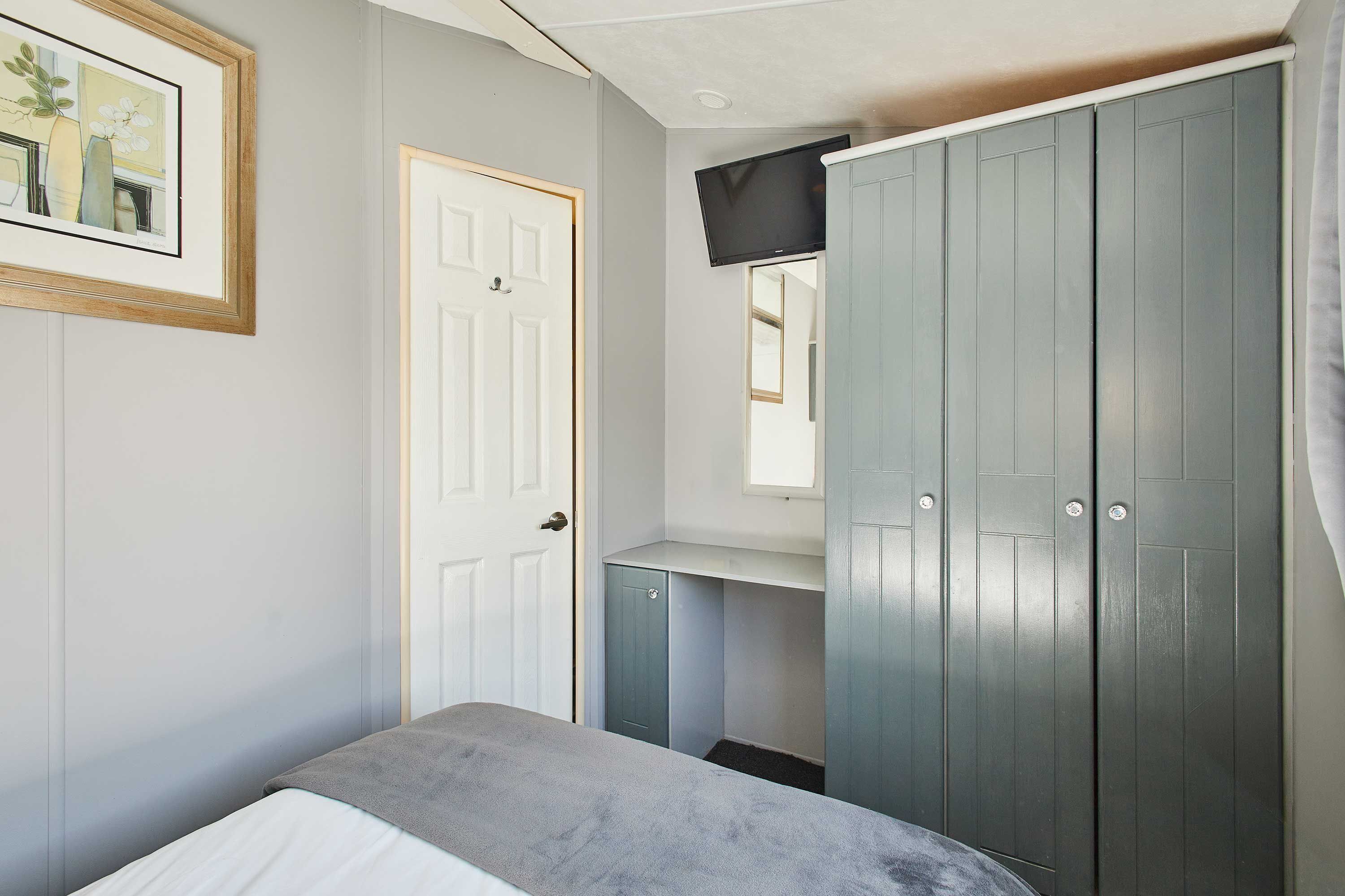 Une chambre à coucher comprenant un lit, une armoire, un bureau et un téléviseur.