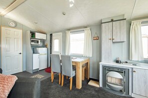 Een praktische keuken met een magnetron, een eettafel met stoelen, een kleine koelkast en een open haard.