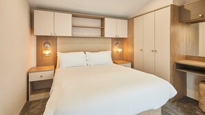 A hotel room with a large bed, wooden headboard, built-in wardrobe, bedside tables, and wall-mounted lamps. - Host Stay Stag Lodge (Pickering)