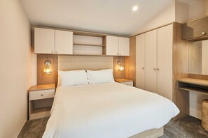 A hotel room with a large bed, wooden headboard, built-in wardrobe, bedside tables, and wall-mounted lights. - Host Stay Stag Lodge (Pickering)