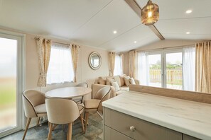 Une pièce chaleureuse comprenant une table à manger, des chaises, un canapé et un coin cuisine.
