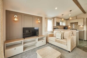 A living room with a TV, sofa, and entertainment unit, a kitchen with cabinets and appliances, and a dining area with a table and chairs. - Host Stay Stag Lodge (Pickering)