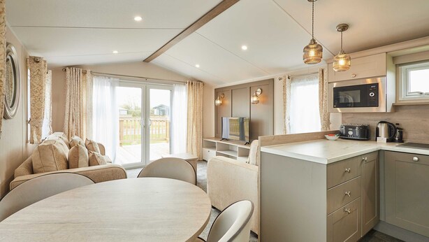 A modern kitchen with a microwave, stove, and dining area with a table and chairs. - Host Stay Stag Lodge (Pickering)