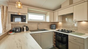 A modern kitchen with a built-in microwave, toaster, and coffee maker, a large sink, and a stove. - Host Stay Stag Lodge (Pickering)