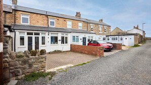 A row of terraced houses with a red car parked in front. - Host Stay Puffin Cottage (Seahouses)