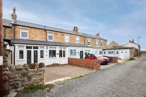 A row of terraced houses with a red car parked in front. - Host Stay Puffin Cottage (Seahouses)