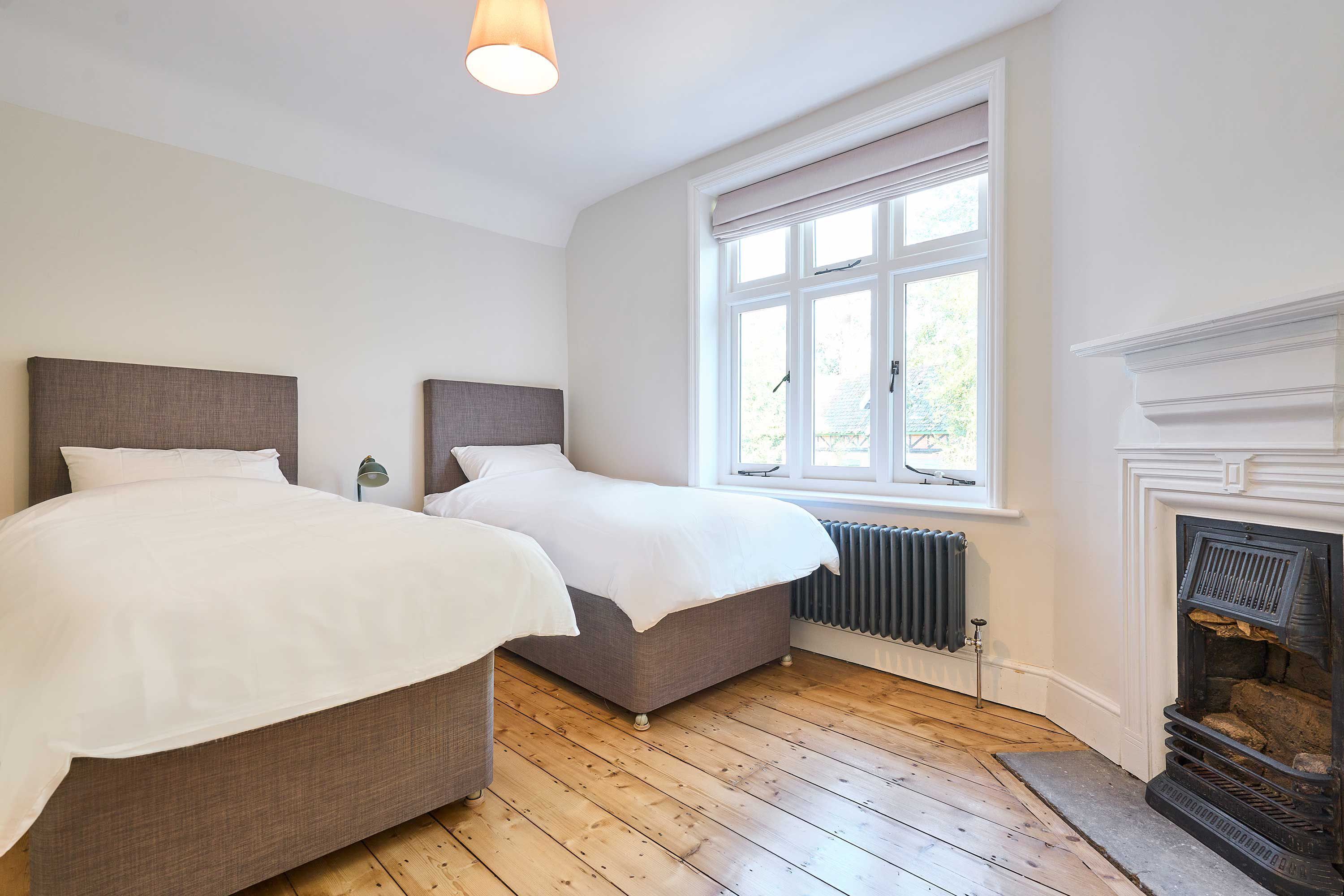 Ein Schlafzimmer mit zwei Betten, einem Kamin und einem großen Fenster.