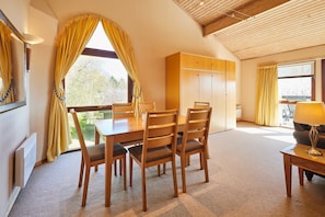 A dining area with a wooden table and chairs, a sofa, and a lamp. - Host Stay Beech Lodge (Grantham)