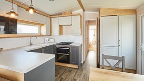 A modern kitchen with a central island, built-in oven, and pendant lighting. - Host Stay Tommy s Lodge (Morpeth)