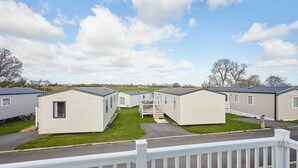 A row of mobile homes with a grassy yard and a white fence in the foreground. - Host Stay Tommy s Lodge (Morpeth)