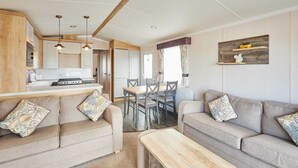 A modern kitchen with a dining area, two sofas with patterned cushions, and a wooden coffee table. - Host Stay Tommy s Lodge (Morpeth)