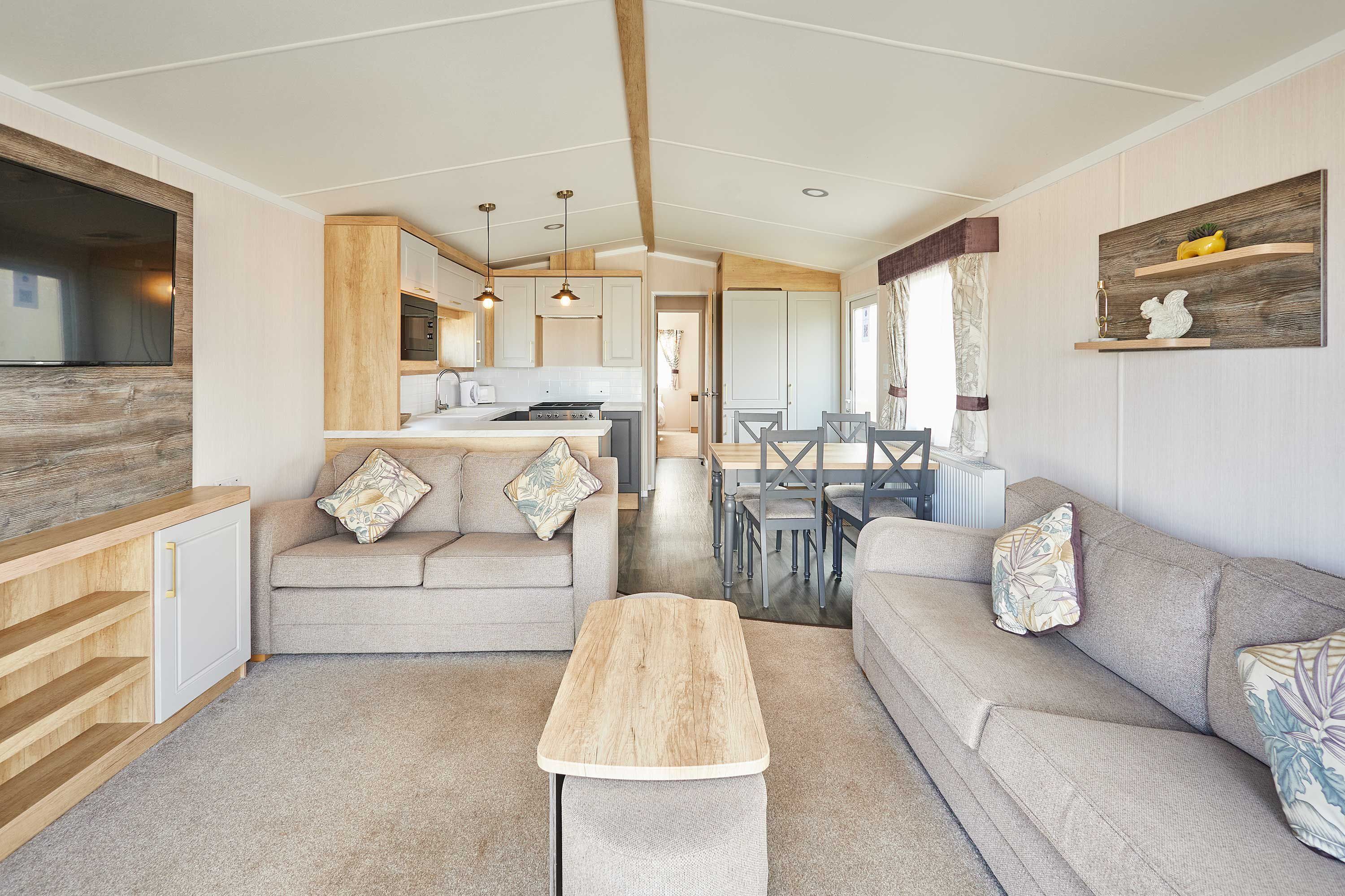 A modern kitchen with wooden cabinets, a dining area with a table and chairs, and a living room with a sofa and a coffee table.