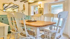 A dining area with a wooden table and white chairs, a mirror, and a door with a sign. - Host Stay Wistermead Cottage (Winkleigh)