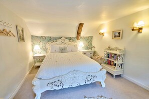 Une chambre à coucher avec un grand lit, deux tables de chevet, une commode, une bibliothèque et des appliques murales décoratives.