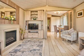 Ein gemütliches Wohnzimmer mit Kamin, Fernseher und Essbereich mit Tisch und Stühlen.