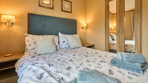 A hotel room with a bed, two wall-mounted lamps, a mirror, and a folded towel on the bed. - Host Stay Fern Lodge (Ipswich)