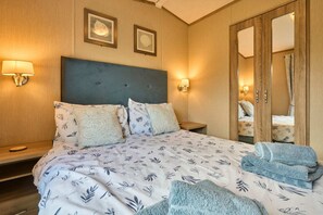 Ein Hotelzimmer mit einem Bett, zwei Wandlampen, einem Spiegel und einem auf dem Bett gefalteten Handtuch.
