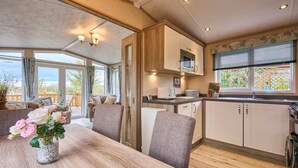 A kitchen with wooden cabinets, a dining table with chairs, and a vase of flowers. - Host Stay Fern Lodge (Ipswich)