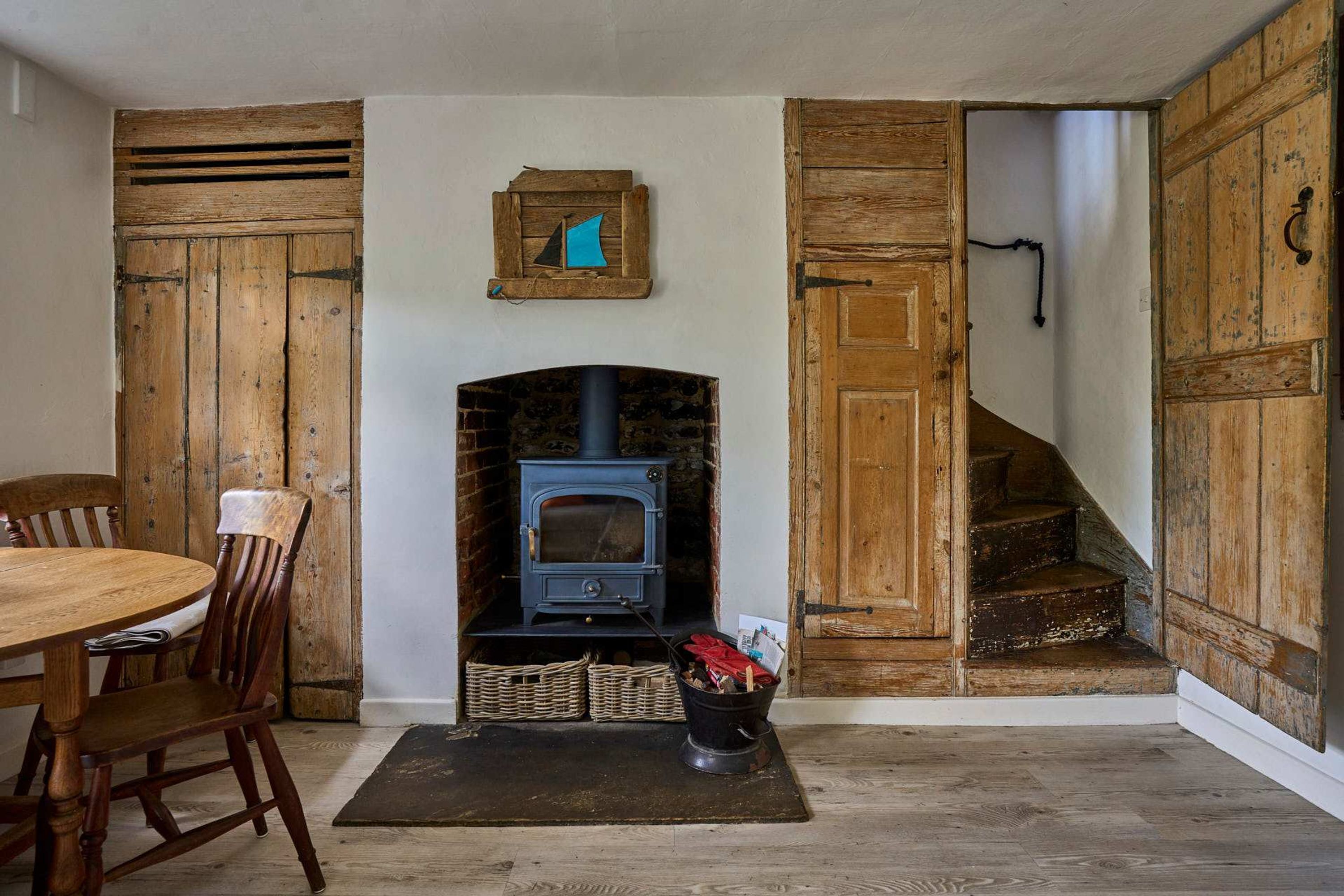 Un intérieur rustique avec une cheminée, des portes en bois, une table à manger avec des chaises et un escalier.