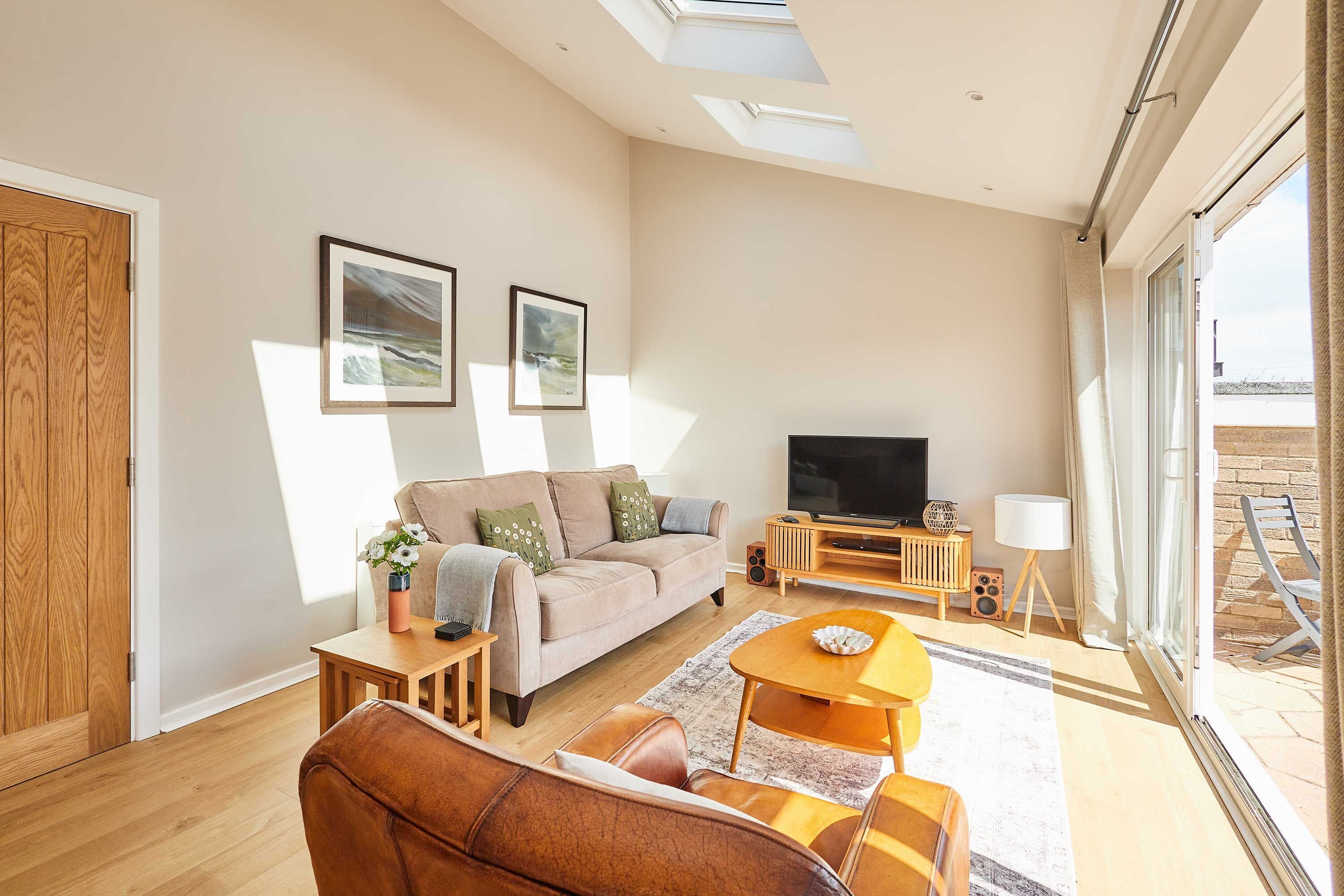 A modern living room with a sofa, coffee table, TV, and artwork on the wall.