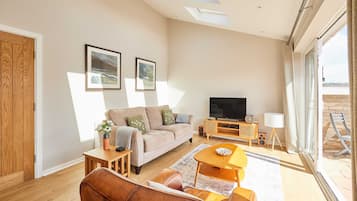 A modern living room with a sofa, coffee table, TV, and artwork on the wall.