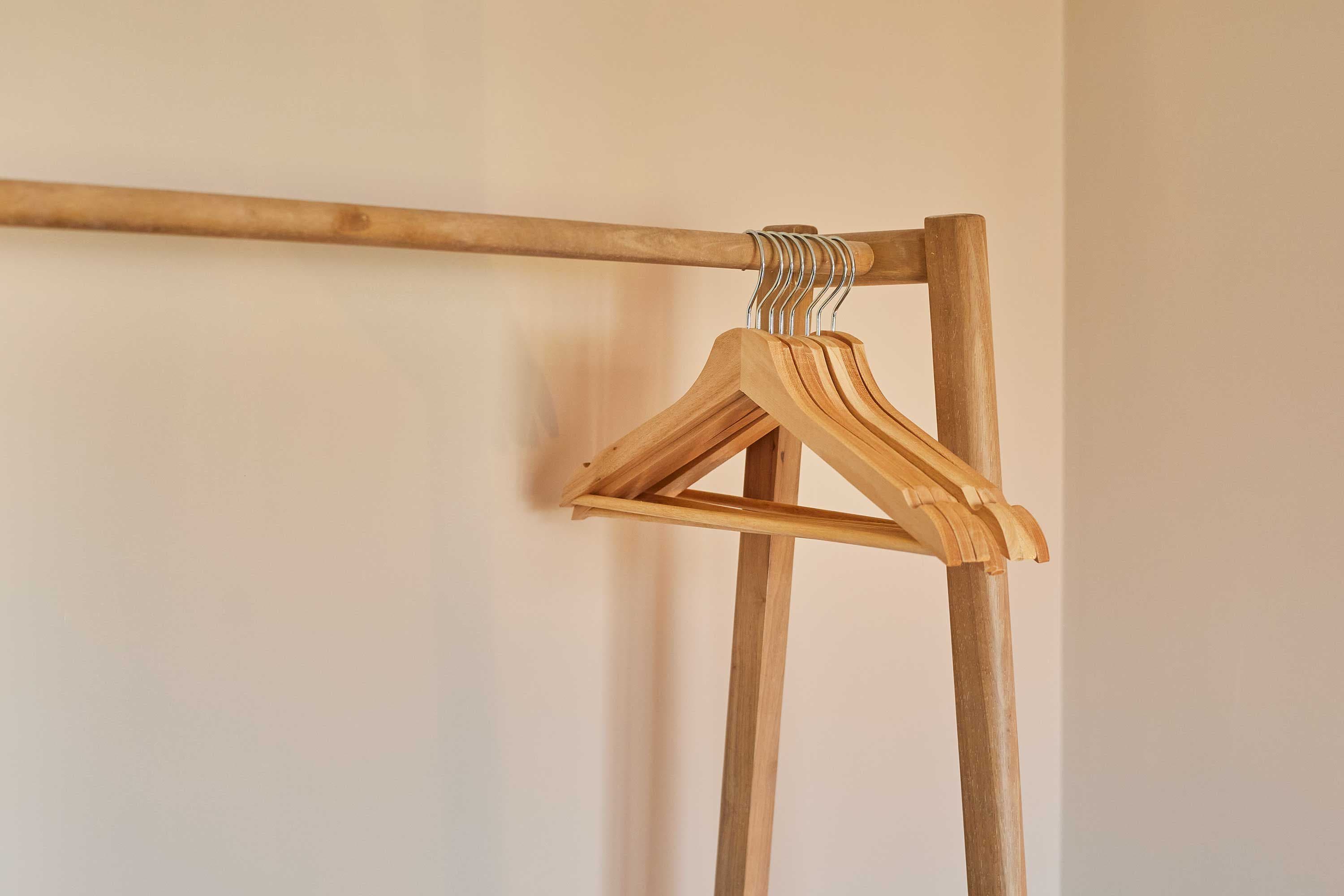 Eine Kleiderstange aus Holz mit einem daran befestigten Holzbügel.