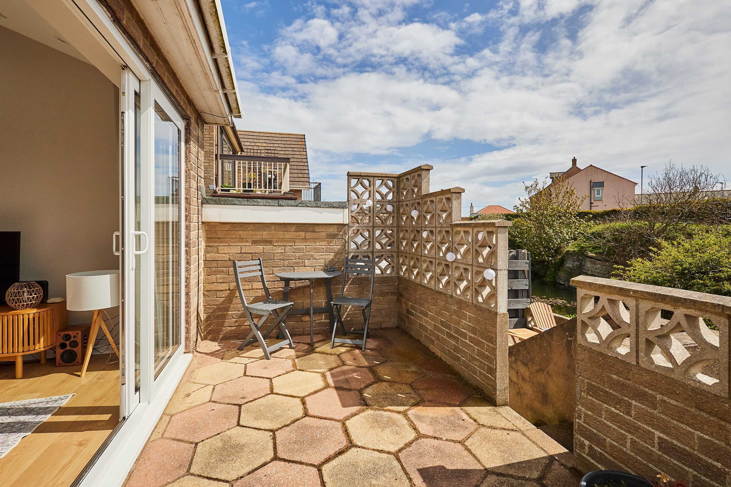 Un patio con tavolo e sedie, una panchina di legno e un recinto decorativo.